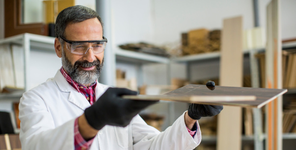 Handsome mature engineer in the laboratory examines ceramic tile